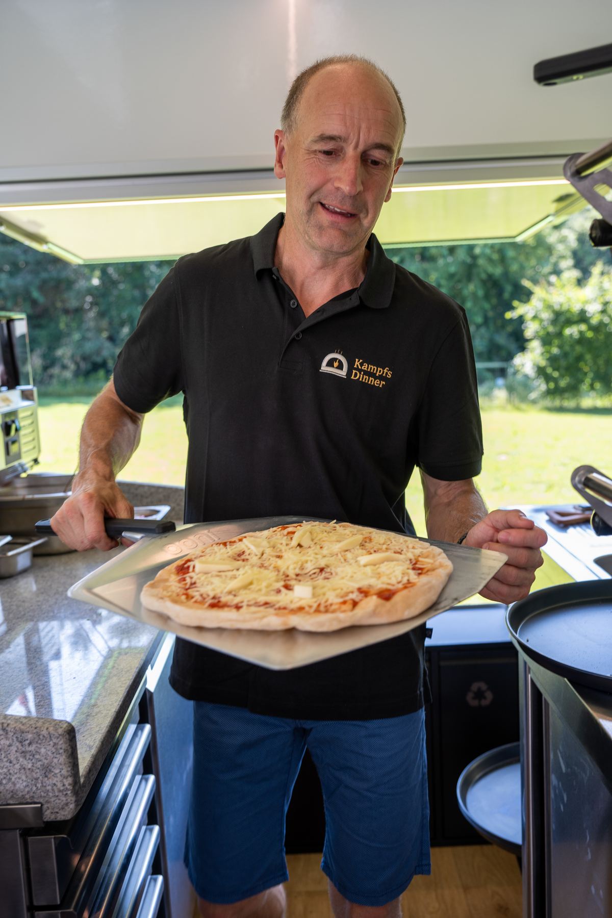 Alexander Kampf, Inhaber von Kampfs Dinner, hält eine frisch gebackene Pizza im Anhänger
