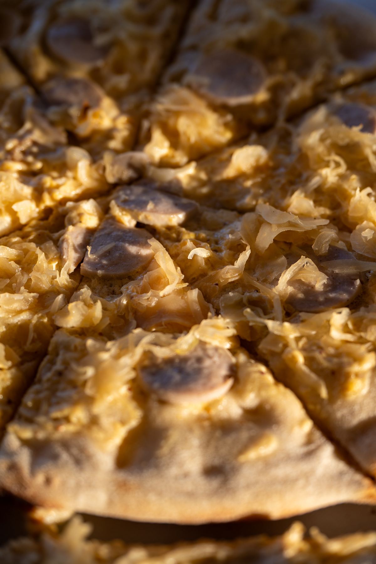 Die Bayerische Pizza von Kampfs Dinner mit Weißwurstscheiben, Sauerkraut und süßem Senf, frisch aufgeschnitten